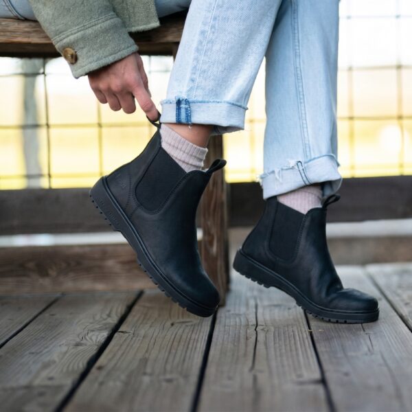 Koel Barefoot Gavien Suede Felt black - dłoń poprawia but na nodze uniesionej nad pomostem