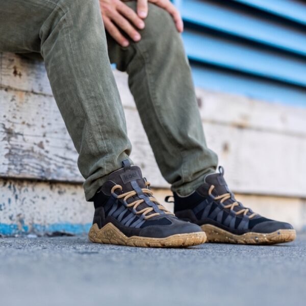 Koel Barefoot Raxo dark grey - dłoń na kolanie, bliski kadr na obie stopy w butach