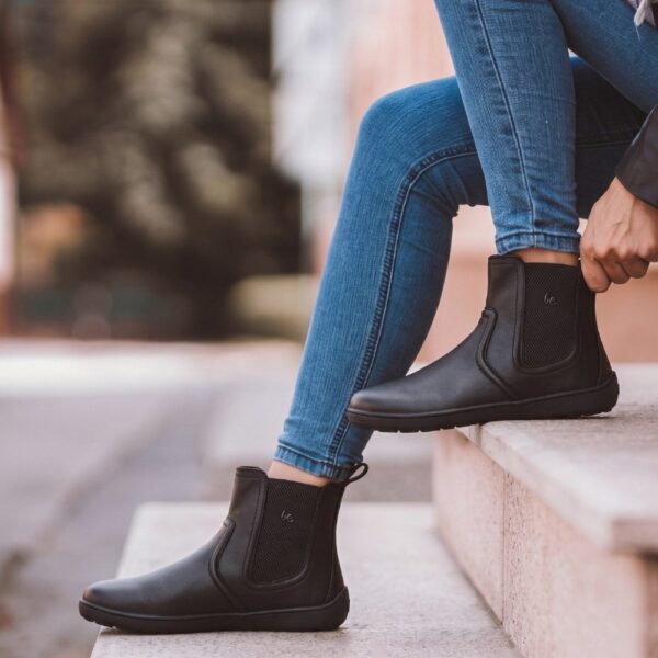 Be Lenka Allure 2.0 black - kobieta na schodach poprawia but, nogi skrzyżowane w jeansach
