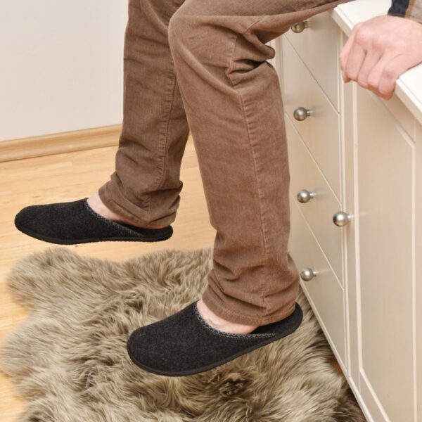 OmaKing Barefoot Slippers Halla dark grey - kapcie na stopach osoby siedzącej na blacie przy dywaniku